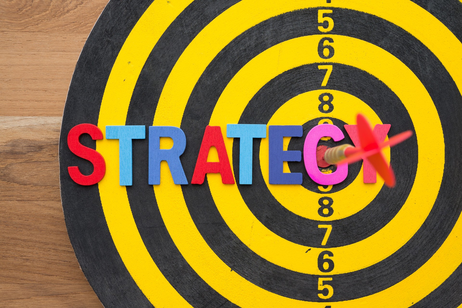 Color alphabets STRATEGY on dartboard background with red darts arrow hit center of target. B
